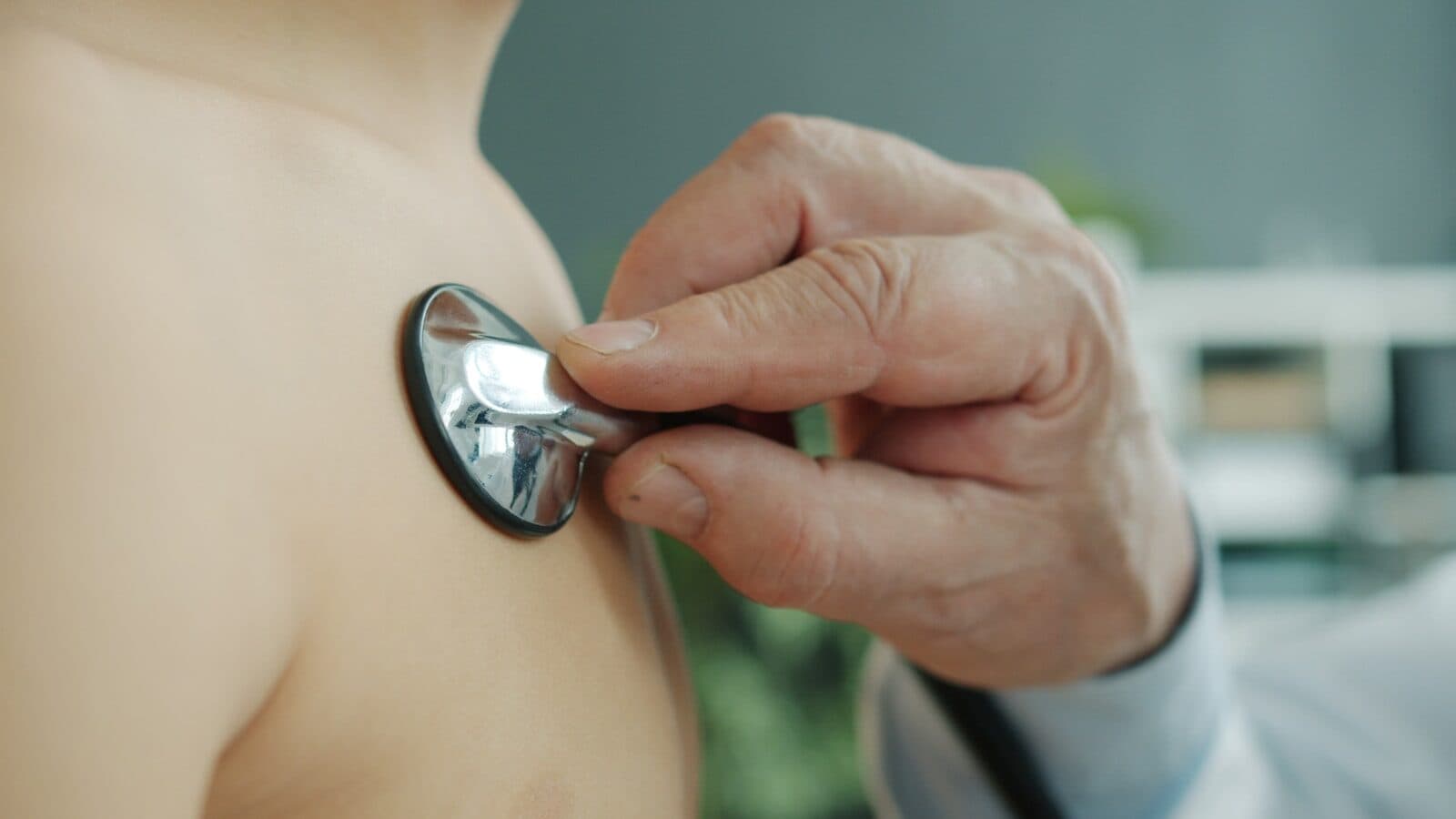Doctor using stethoscope to examine patient's chest