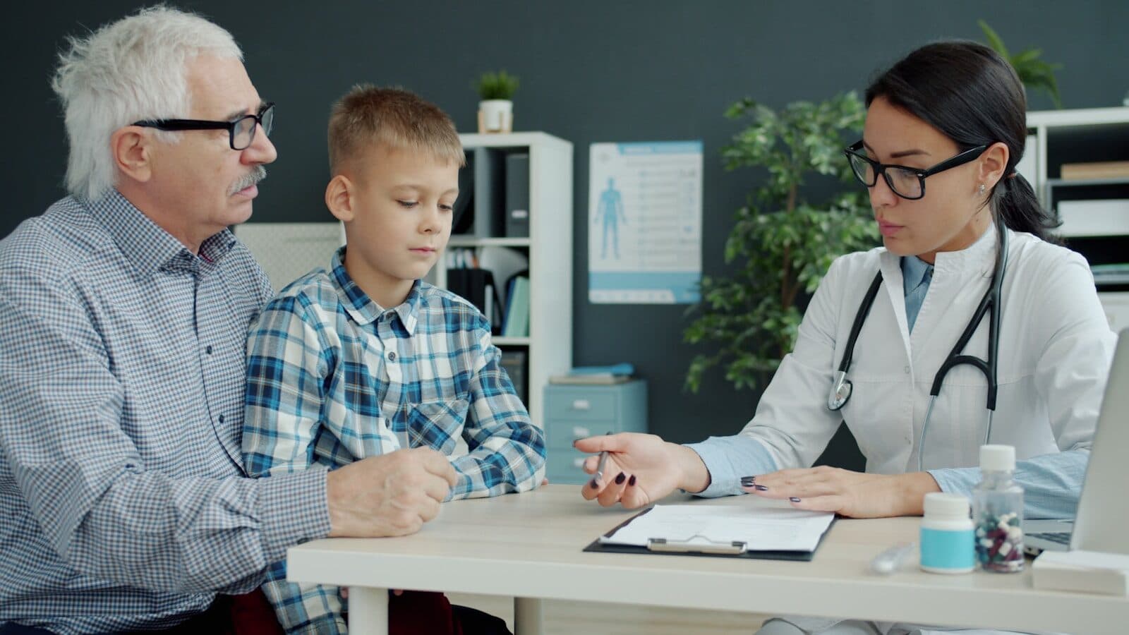 Doctor consults with grandfather and grandson in office.