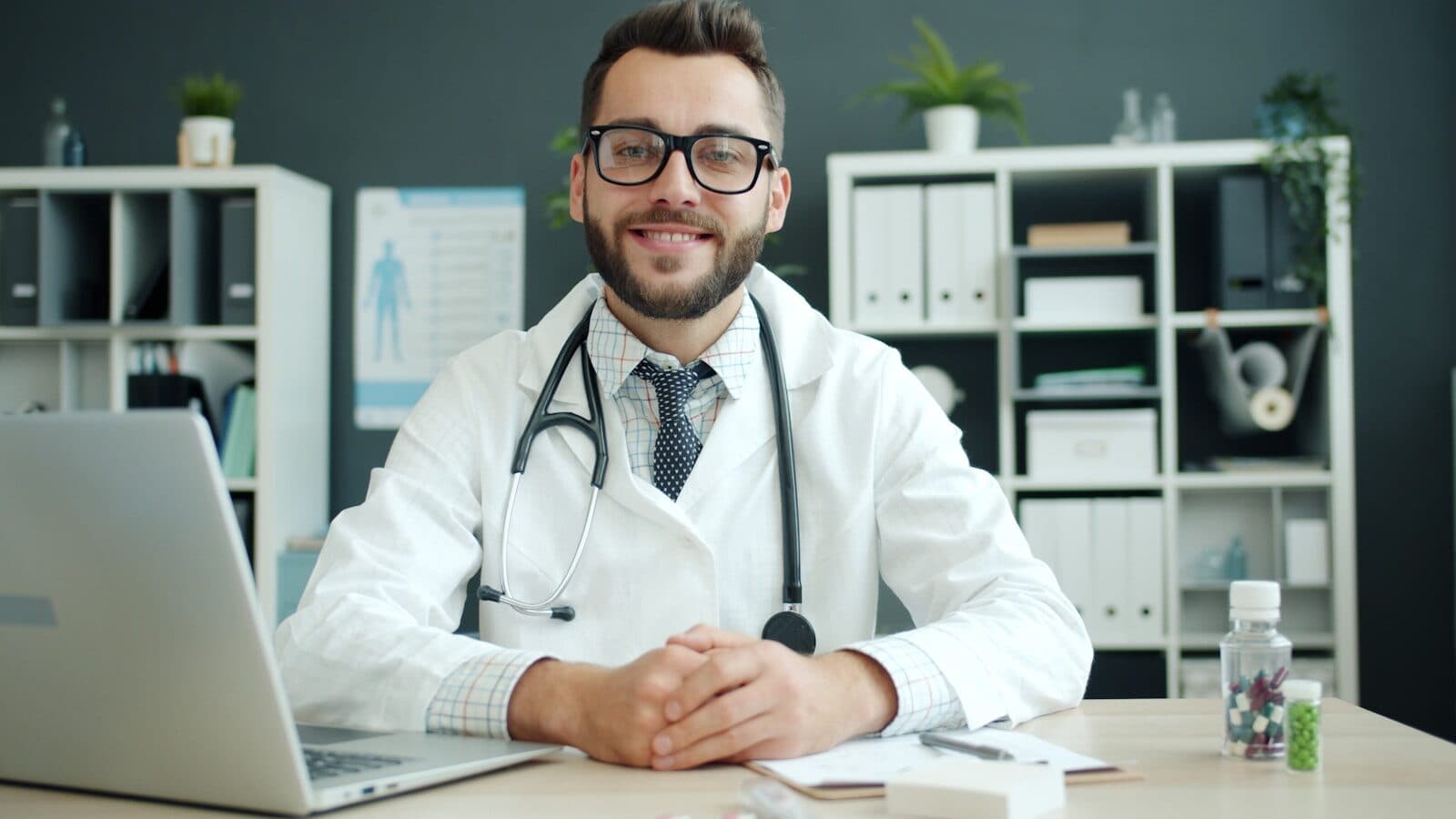 Doctor wearing a stethoscope sits at a desk.